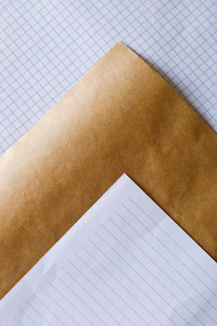 A close-up view of a stack of graph, lined, and kraft paper sheets arranged in a minimalist style.